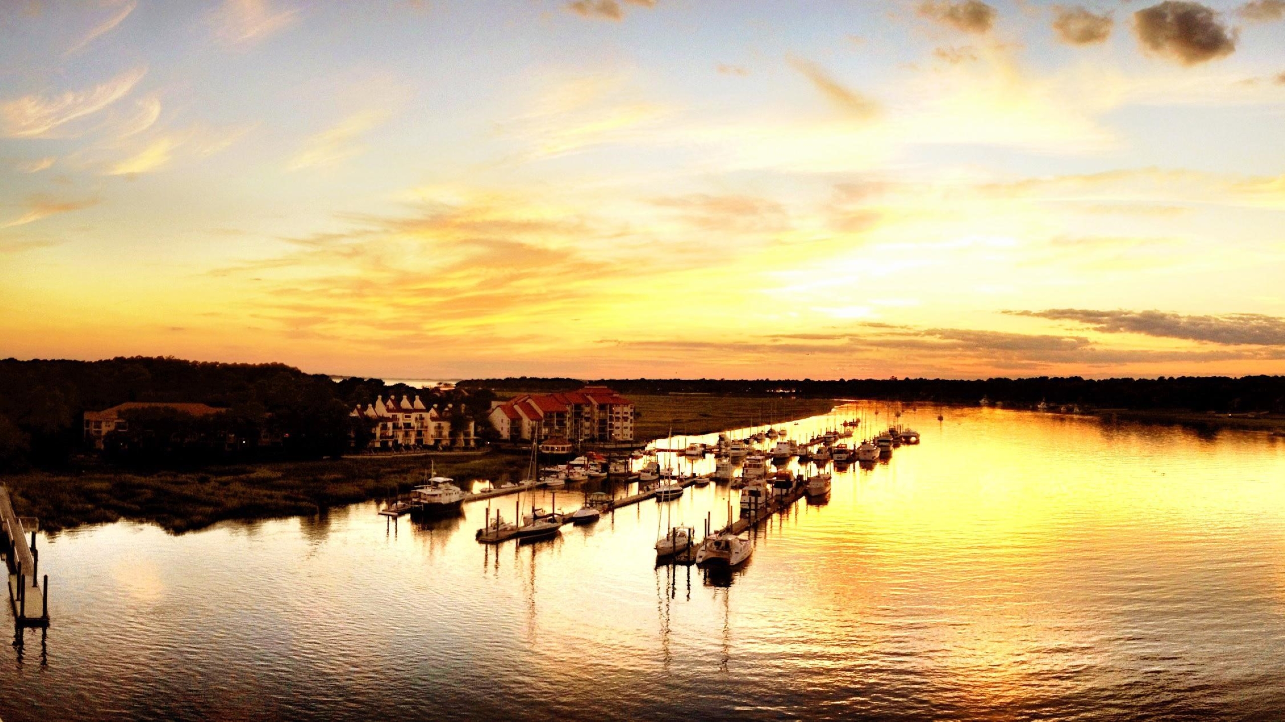 Docked boats on river at sunset